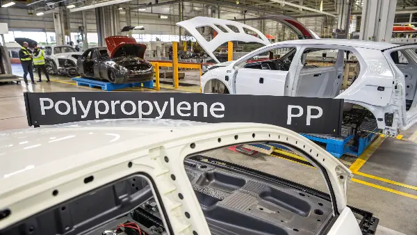 An injection molding machine producing a black polypropylene car bumper.