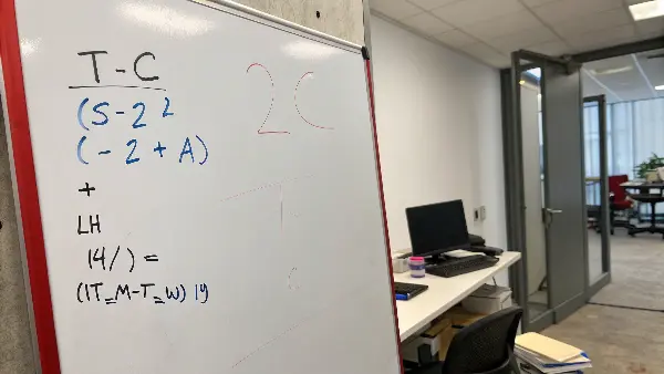 A whiteboard with a mathematical formula for injection molding cooling time written on it